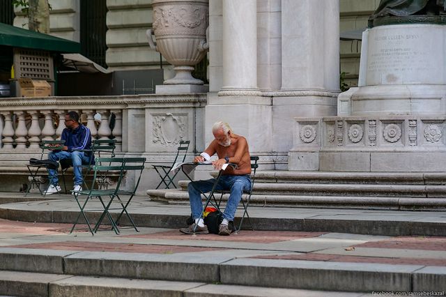 a shirtless guy sits in Bryant Park